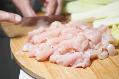 Tahtada çiğ tavuk doğrarken yanında taze kereviz sapları..