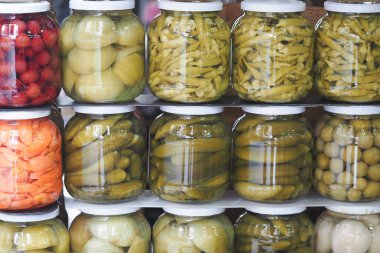 Bir markette kavanozlarda çeşitli sebze turşusu düzenlenir..