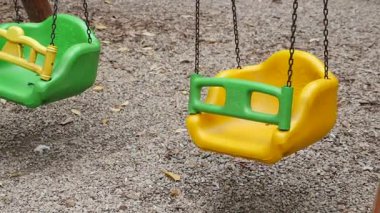 Parlak sarı ve yeşil salıncaklar çocuklar için sessiz bir oyun alanında asılı.