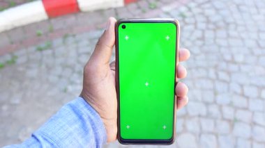 Güneşli bir günde açık havada yeşil ekran ile akıllı bir telefonu tutmak.