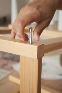 Bir el montaj sırasında tahta bir bacağa vida takıyor..