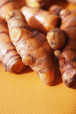 Parlak turuncu bir yüzey üzerinde zerdeçal kökleri zengin renkler ve dokular gösterir.