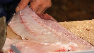 Becerikli bir aşçı pazarda satırla balık doğrar..