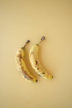 Kahverengi benekli iki olgun muz sade bir arka planda dizilmiş..