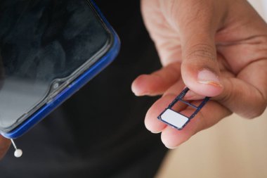 Bir el, akıllı telefona yerleştirmeye hazırlanırken bir SIM kartı tutar.