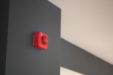 Karanlık bir duvara monte edilmiş parlak kırmızı alarm ışığı içerideki güvenlik görüntülerini güçlendirir..