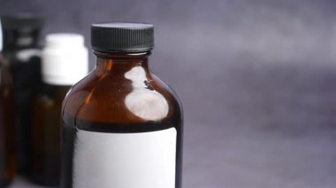 Gri yüzeyde kahverengi ilaç şişesi,