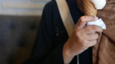 Sıradan bir kafe ortamında rahatlarken bir insan dondurma külahı tutar..