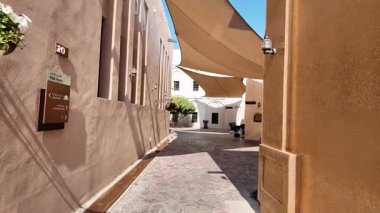 Çiçekler ve güneşliklerle süslenmiş güzel bir ara sokak keşfet..