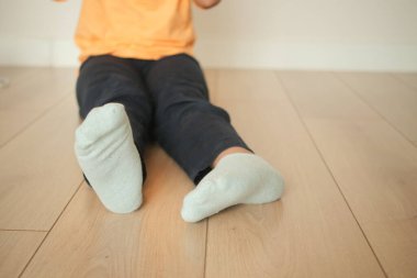 Turuncu tişörtlü çocuk yerde oturuyor, oyun zamanı aktiviteleriyle meşgul..