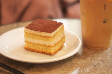 Kafe masasında bir dilim kek ve buzlu kahve keyiflidir..