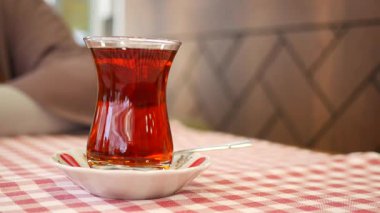 Sıcak bir bardak çay kareli bir masa örtüsünde oturmuş eğlenmeyi bekliyor..