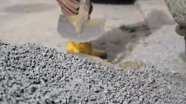 Sarı çizmeli işçi inşaat alanında çakıl başında duruyor..