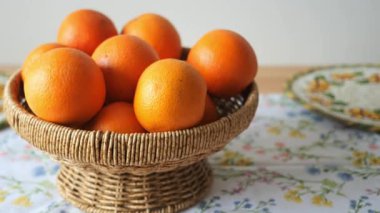 Portakallar renkli bir masa örtüsünün üzerinde parlak bir sepetin içinde otururlar..