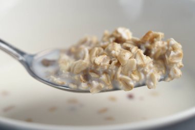 Bir kaşık dolusu yulaf ezmesine yakın çekim. İçinde kremalı dokular ve taneler var..