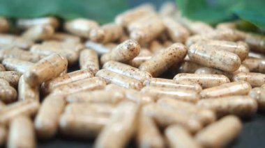 Çeşitli doğal maddelerin yer aldığı bitkisel kapsüllerin yakın çekim görüntüsü.