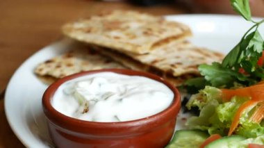 Düz ekmek, yoğurt sosu ve taze salatanın tadını çıkarın..