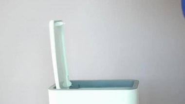 Bir el, şık bir çöp kutusunu rahatça açmak için dokunmatik sensöre basar..