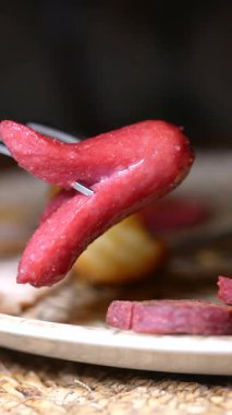 Tahta bir tabakta, yanında dilimlenmiş parçalarla lezzetli kırmızı bir atıştırmalığın tadını çıkarıyorum..