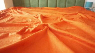 Parlak turuncu çarşaf yatak odasına yayılıyor..