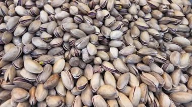 Kalabalık bir pazarda sergilenen büyük şam fıstığı yığını.