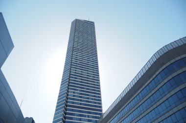 Yüksek bir gökdelende açık mavi gökyüzüne karşı modern tasarım sergileniyor.