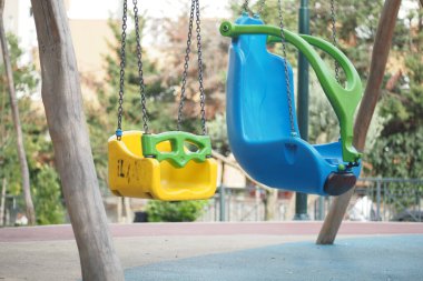 Parktaki sağlam zincirlerden sarkan parlak renkli iki salıncak..