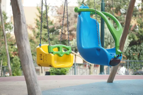 Parktaki sağlam zincirlerden sarkan parlak renkli iki salıncak..