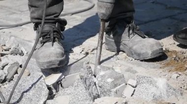 İşçi şehir merkezinde kaya matkabıyla beton kaldırımı yıkıyor.