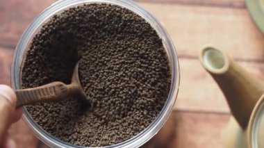 Kaşık bir konteynırdan gevşek çay koparır .