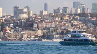Arkasında çarpıcı bir şehrin silueti olan bir tekne suyun üzerinde sorunsuzca hareket eder..