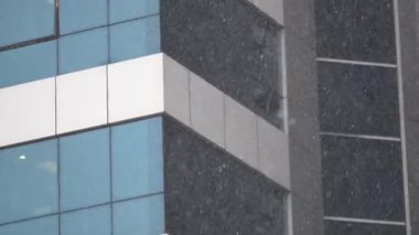Kar, kış boyunca hareketli bir şehirde modern binaları kaplar..