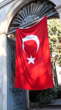 Canlı bir köşedeki süslü bir kemerde büyük bir Türk bayrağı sallanıyor.