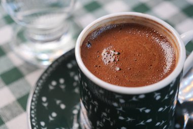 Kareli masa örtüsüyle rahat bir kafede Türk kahvesinin tadını çıkarıyorum..