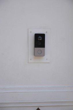 Temiz, beyaz bir duvara parlak bir kapı zili kurulumu modern dekorasyonu güçlendirir..