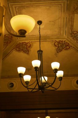 Sıcak ışık, tarihi bir ortamda klasik bir avizeden yayılır..