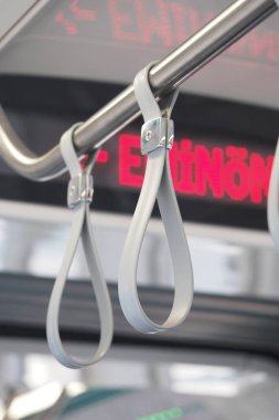 Bir otobüsün tavanında asılı duran tutamaklar, yolculara destek sağlıyor..