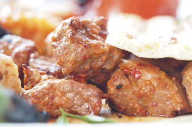 Şefkatli ızgara et dışarıda garnitürle servis edilir..