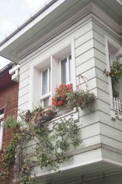 Renkli çiçekler ve yeşillik ahşap bir evin büyüleyici balkonunu süslüyor..