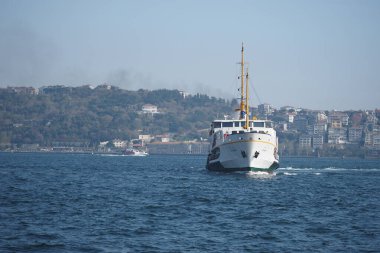 İstanbul 'un mavi sularından bir feribot geçiyor, tepelerle çevrili..