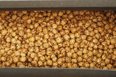 Kavrulmuş nohut, metal bir kabı doldurur, altın kahverengi renklerini sergiler..