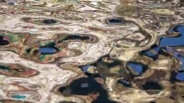 Renkli yansımalar su yüzeyinde dans ederek soyut tasarımlar oluşturur..