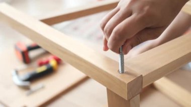Tahta mobilyaları vida ve temel gereçleri kullanarak monte eden kişi.