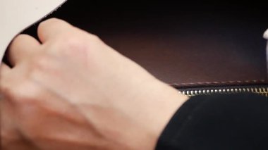 Biri kahverengi bir fermuar çantasından bir cüzdan alır..