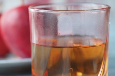 Altın elma suyu taze kırmızı elmaların yanında temiz bir bardağa dökülür..