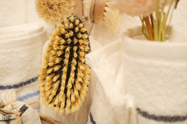 Havlular ve dekoratif eşyalar arasında doğal bir temizlik fırçası asılı..