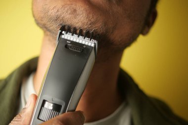 Kapalı mekanda elektrikli makina kullanarak yüz kıllarını tek tek kesiyor..