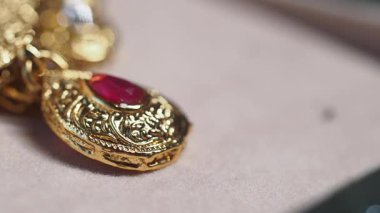 Süslü bir tasarım ve parlak kırmızı bir mücevher içeren zarif bir altın kolye..