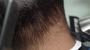 Yetenekli bir stilistin, hareketli bir kuaförde saçları titizlikle budamasını izleyin..