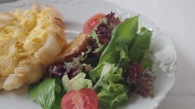 Sabah yemeğinde sıcak kruvasan, çırpılmış yumurta ve salata var..